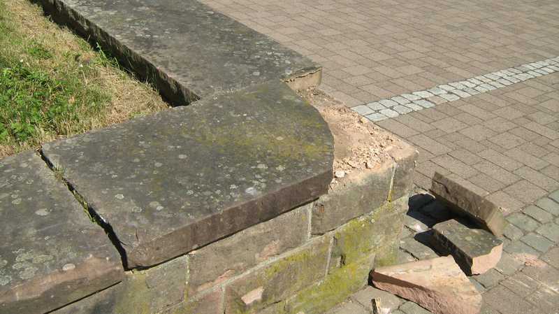 Die beschädigte Sandsteinmauer