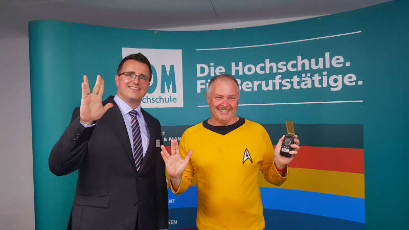 Felix von Dobschütz, Gesamt-Geschäftsleitung FOM Hochschulzentrum Frankfurt, mit dem Referenten Dr. Hubert Zitt beim traditionellen Star Trek-Gruß. (Foto: FOM Hochschule/Claudia Becker)