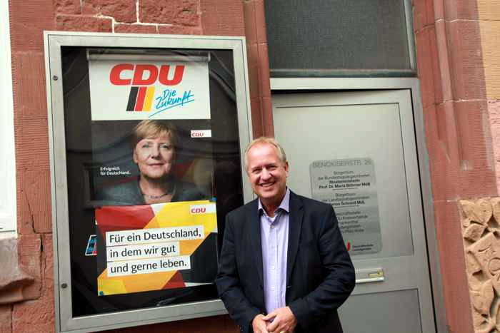 OB-Kandidat Dr. Peter Uebel vor einem Wahlplakat seiner Parteikollegin Angela Merkel
