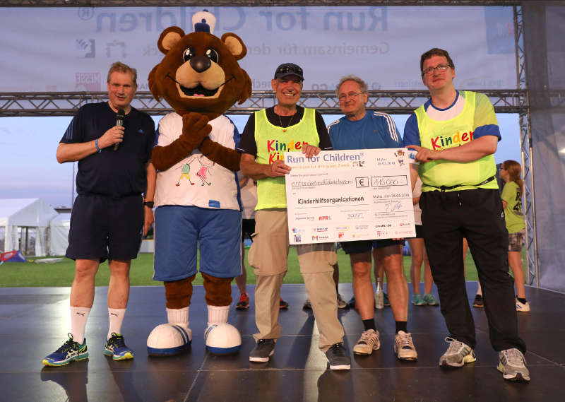 SCHOTT Vorstandsvorsitzender Dr. Frank Heinricht, das Maskottchen SCHOTTi sowie die Mediziner Dr. Helmut Peters, Dr. Rolf Beetz und Dr. Helge Gallwitz, die das Organisationsteam bei der Zuweisung der Spenden unterstützen, präsentieren den Spendenscheck. (Foto: SCHOTT / Alexander Sell)