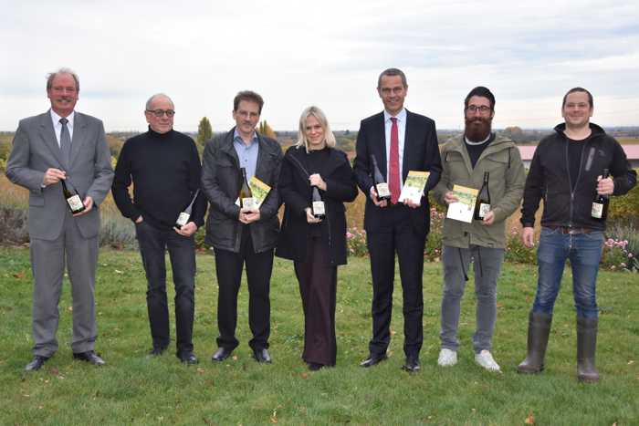 Freuen sich über die weitere Aufwertung der Aktion „Landauer Hochzeitswingert“: Standesamtsleiter Leander Völlinger, Theodor Pfaffmann vom WEIN.GUT.PAN, Peter Büchner von der Galerie Z, Maxime Früh von der Firma Ehrmann, Bürgermeister Dr. Maximilian Ingenthron, Christian Cambeis von der Firma Ehrmann und Thomas Pfaffmann vom WEIN.GUT.PAN (v.l.n.r.). Quelle: Landau in der Pfalz