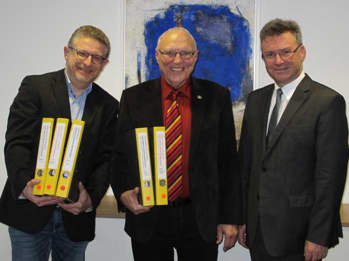 Postoberrat a. D. Manfred Biedert (Mitte) präsentiert zusammen mit Kreisarchivar Alexander Rantasa beispielhaft einige Sammlungsordner bei der Übergabe der Schenkung an Landrat Dr. Achim Brötel Foto: Landratsamt