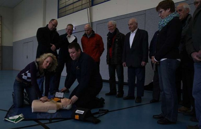 Schulleiterin der Carl Orff Grundschule Maren Neuendorf und Feuerwehrsanitäter Ralf Mittelbach bei der AED Übung. Im Hintergrund von links Thomas Bader CDU, Abteilungskommandant Sulzbach Karsten Fath.