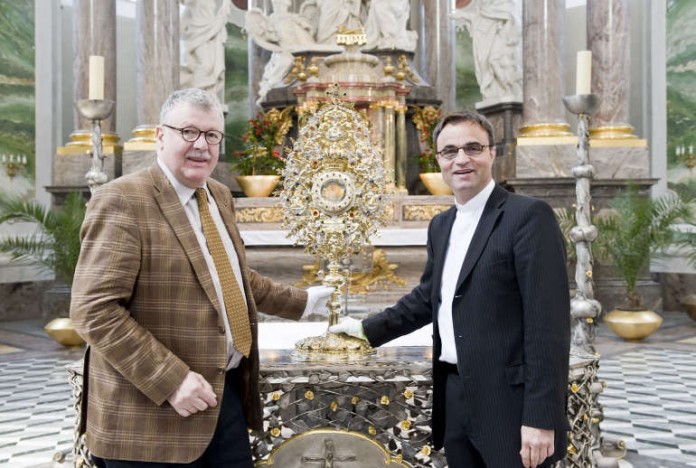 Dr. Hans-Jürgen Buderer, Direktor der rem für Kunst- und Kulturgeschichte, übergibt die Sonnenmonstranz in der Jesuitenkirche an Dekan Karl Jung.