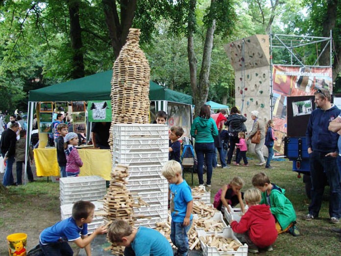 Geschicklichkeit bewiesen Jungen und Mädchen beim Bauen eines riesigen Turms aus Holzbausteinen.