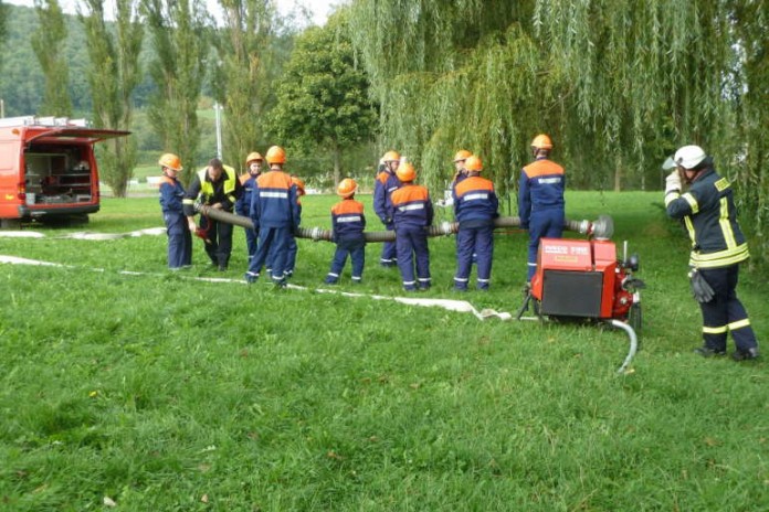 Die Jugendliche lassen die fertige Saugleitung zu Wasser.