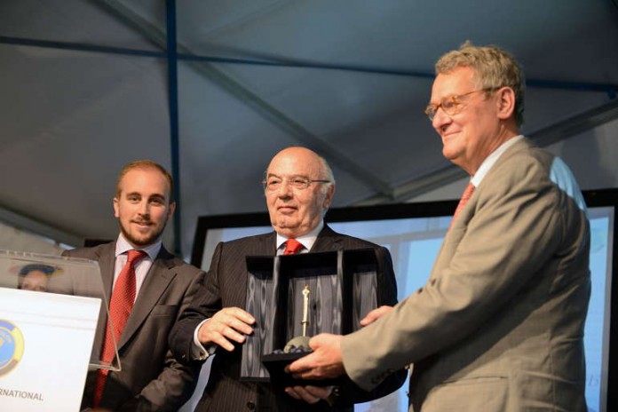 IOC-Mitglied Lambis Niolaou (Mitte) überreicht Prof. Dr. Norbert Müller (rechts) den goldenen Fackelstab