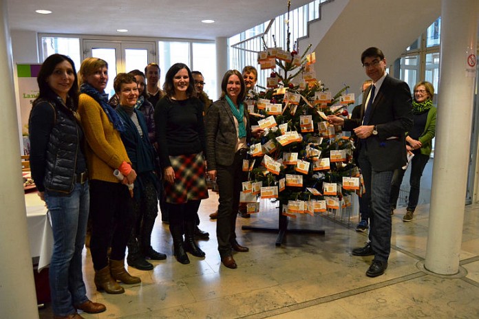 Bürgermeister Thomas Hirsch (rechts) gemeinsam mit Susanne Burgdörfer (links neben Tannenbaum) vom Haus der Jugend und Vertretern der sozialen Einrichtungen beim aufhängen der Wunschkarten.