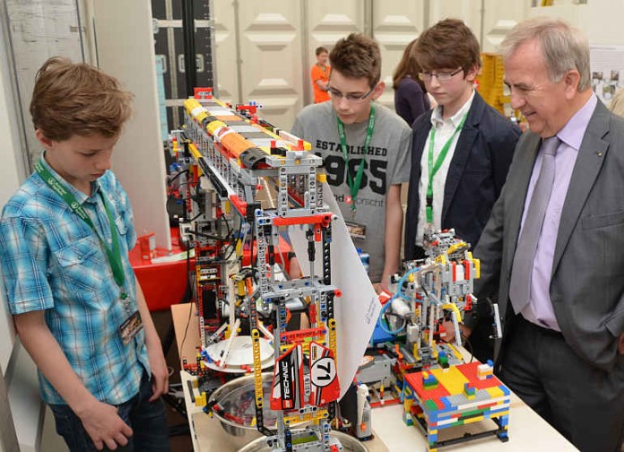 Fabian Specht, Vincent Schmandt und Joseph Schmid (v.li.) führen Landrat Claus Schick ihren Abspülroboter vor