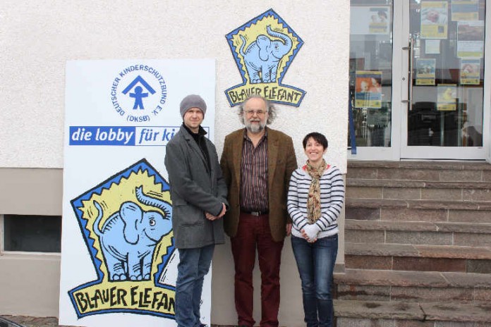 BLAUER ELEFANT im neuen Gewand: Marc Depuhl und Julia Grass von der Werbeagentur „Point of Media“ überreichen Heinrich Braun, Geschäftsführer des Kinderschutzbundes, die fertigen Schilder für die Fassade des Kinderhauses