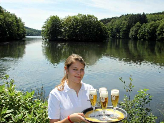 Die "Krombacher Insel" kann man jetzt live erleben - darauf ein Krombacher! Aline Gansee, Mitarbeiterin der Krombacher Brauerei, serviert frischgezapftes Krombacher Pils zur Eröffnung des Aussichtspunkts "Krombacher Insel".