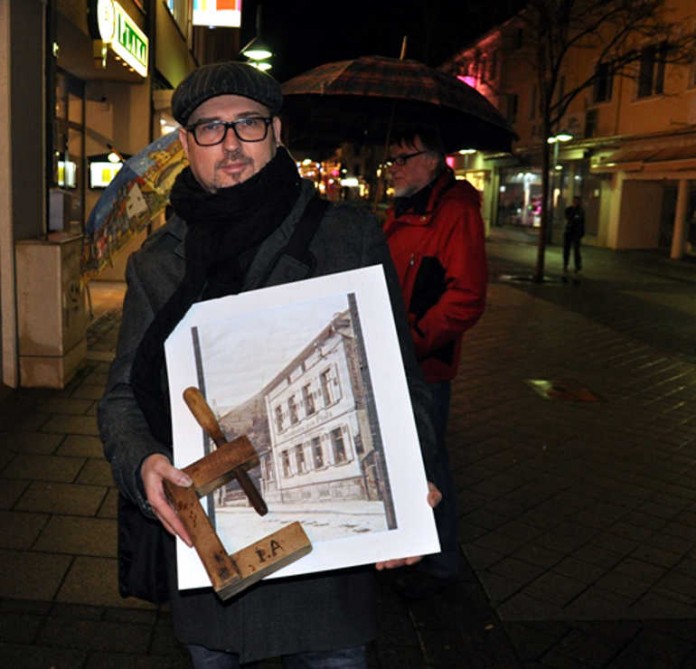 Jens Hübner mein einem Foto vom Gasthaus „zur Pfalz“, das ihm Steffen Kaul aus seiner Sammlung zu Verfügung stellte, und eine hölzerne Schraubzwinge aus der Küferei von Jakob Albrecht
