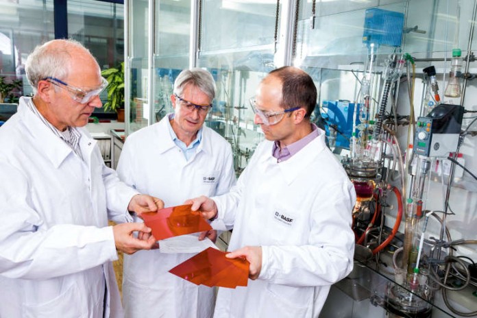 Dr. Hans Reichert (Mitte), Leiter der Farbstoffforschung bei BASF, begutachtet mit seinen Kollegen Ger de Keyzer (links) und Dr. Roman Lenz (rechts) Applikationsmuster des roten Farbfilterpigments
