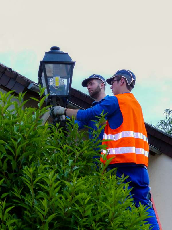 Marcel Hayen und Nils Kreischer montieren die umgerüstete historische LED-Straßenleuchte auf dem bestehenden Mast. (Foto: Westnetz GmbH)