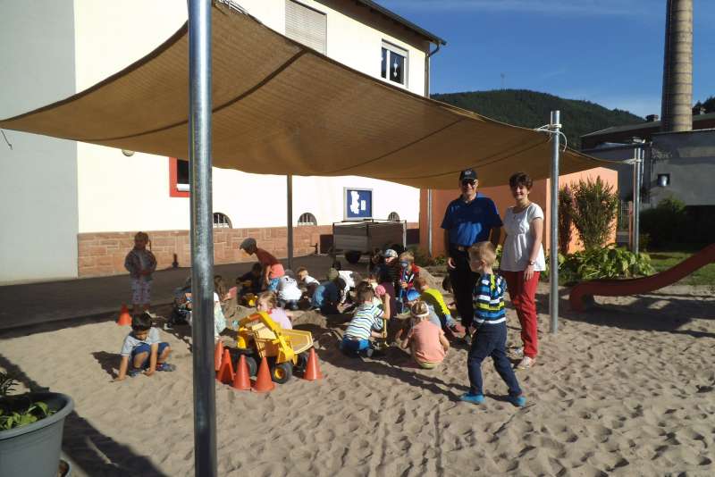 Bauunternehmer Gerd Mersinger mit Kitaleitung Elke Lorenz-Schindler und den glücklichen Kitakindern unter dem neuen Sonnensegel (Foto: Katholische Kindertagestätte St. Lambertus)