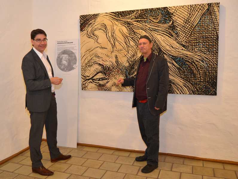 Oberbürgermeister Thomas Hirsch und Prof. Dr. Diethard Herles vor einem der Kunstwerke, die aktuell im Frank-Loebschen Haus zu sehen sind. Das Bild zeigt den von Thomas Nast erfundenen modernen Weihnachtsmann. Dieses Motiv, sagt Herles, sei so bekannt, dass der Betrachter es selbst dann noch erkennen könne, wenn – wie in diesem Fall – nur ein Ausschnitt zu sehen sei.