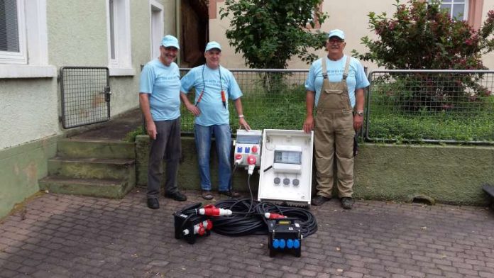 Friedrich Reinhardt und Uwe Trautwein überreichen Ortsbürgermeister Rudolf Haas die neue Stromverteilungsanlage für den Rathausplatz in Wonsheim. (Foto: RWE International SE)