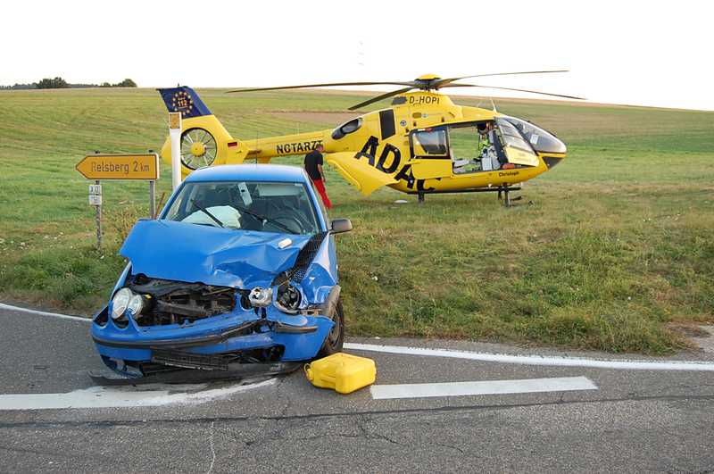 Eines der schwer beschädigten Unfallfahrzeuge vor dem Rettungshubschrauber