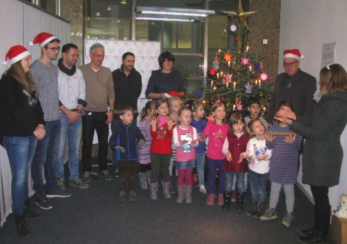 Kinder des Kindergartens St. Paul mit ihrer Leiterin Beate Zepezauer (rechts) sowie Chantal Schalm u. Maximilian Greil, Amt für Familie und Soziales, Mitarbeiter John-Deere Yusuf Kodal, Herbert Keßler, Luca Calò, Oberbürgermeisterin Cornelia Petzold-Schick und Fachsbereichsleiter Patrik A. Hauns vor dem bunt geschmückten Weihnachtsbaum. (Foto: Stadt Bruchsal)