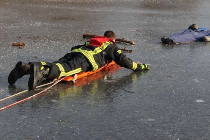 Ein Feuerwehrmann nähert sich dem im Eis Eingebrochenen mit einem Spineboard (Foto: Feuerwehr)