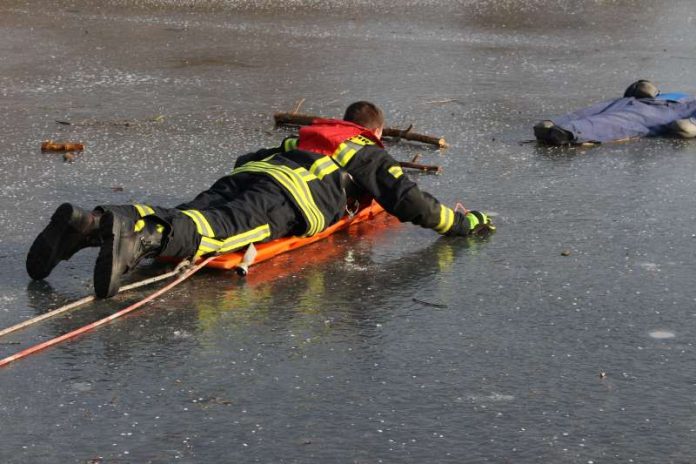 Ein Feuerwehrmann nähert sich dem im Eis Eingebrochenen mit einem Spineboard (Foto: Feuerwehr) Ein Feuerwehrmann nähert sich dem im Eis Eingebrochenen mit einem Spineboard (Foto: Feuerwehr)