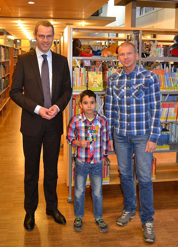 Bürgermeister und Kulturdezernent Dr. Maximilian Ingenthron (l.) überreichte dem jungen Gewinner Amir Kamel im Beisein seines Vaters Miroslaw Fritsche (r.) den Buchscheck und gratulierte ihm zu seinem Erfolg. (Foto: Stadt Landau in der Pfalz)