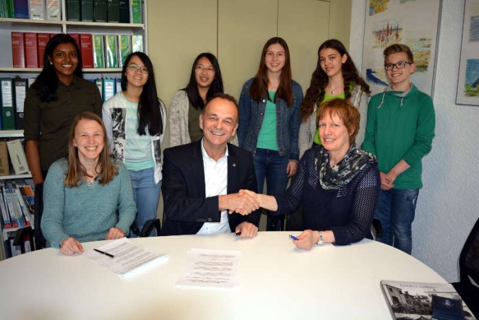 Oberstudienrätin Andrea Frick, Landrat Dr. Fritz Brechtel und Schulleiterin Ariane Ball bei der Vertragsunterzeichnung, im Hintergrund Schüler der Projektgruppe, sog. Energiescouts. (Foto: Kreisverwaltung Germersheim)