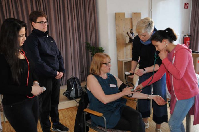 Susanne Emanuel-Semisch, Pflegedienstleiterin des Lorenz-Wertmann-Hauses in Wiesbaden-Kohlheck zeigt der Schülerin, wie man richtig Blutdruck misst. (Foto: Sabine Eyert-Kobler)