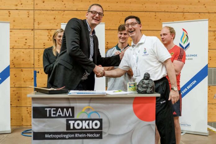 OSP Leiter Daniel Strigel (links) und Conor Troy (rechts) besiegeln die Zusammenarbeit. Im Hintergrund Stabhochspringerin Lisa Ryzih und die beiden Rugby-Nationalspieler Niko Müller und Phil Szezegin (Foto: Tobias Dittmer)