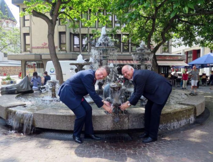 OB Löffler und KSB-Vertriebsleiter Haag gönnen sich zur Wiederbelebung des Brunnens ein Glas Wein aus der Elwedritschebrust. (Foto: Stadtverwaltung Neustadt)