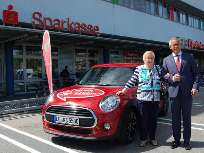 Andreas Ott, Vorsitzender des Vorstandes der Sparkasse Rhein-Haardt mit der Gewinnerin Renate Freymeyer vor dem symbolisch bereitstehenden MINI One – zur Verfügung gestellt durch das Autohaus Klaus Scheller. (Foto: Sparkasse Rhein-Haardt)