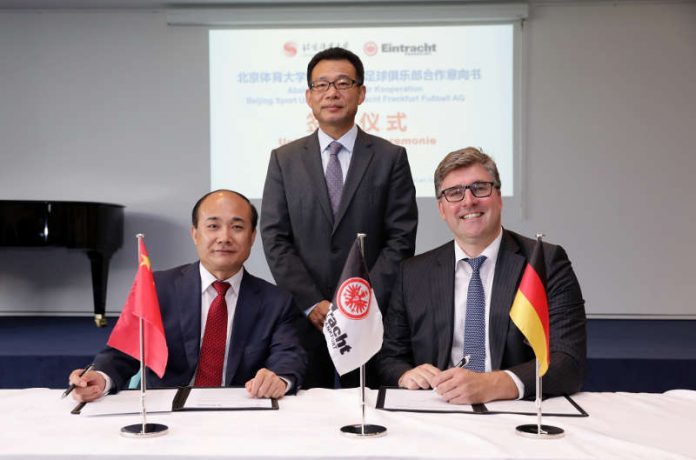 Generalkonsul Wang Shunqing (stehend) bei der Vertragsunterzeichnung von BSU-Direktor Cao Weidong und Axel Hellmann. (Foto: Eintracht Frankfurt)