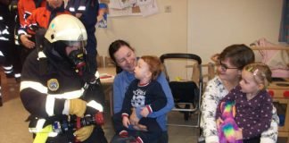 Feuerwehrmann Dennis Stark zeigt Castiel (li.) und Leonie (re.) die Bedienung eines Hohlstrahlrohres in voller Schutzausrüstung (Foto: Feuerwehr Bad Kreuznach)