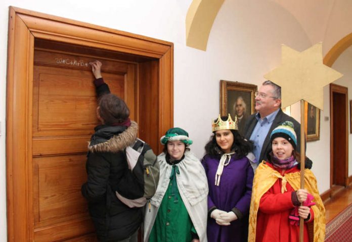 Sternsinger aus der Dompfarrer Pax Christi bringen den Segen in das Bischöfliche Ordinariat in Speyer. Mit Kreide schreiben sie auf die Tür zu den Arbeitszimmern von Generalvikar Dr. Franz Jung und Kanzleidirektor Wolfang Jochim (im Bildhintergrund) den Segensspruch „Christus mansionem benedicat – Christus segne dieses Haus“. (Foto: Bistum Speyer)