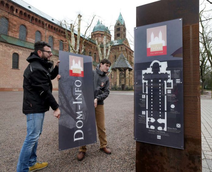 Anlaufstelle für alle Dom-Besucher mit neuer Benennung und Beschilderung, Claudio Usnik, printline und Bastian Hoffmann, Leitung Dom-Besuchermanagement bei der Montage der neuen Schilder (Foto: Klaus Landry © Domkapitel Speyer)