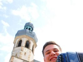 Junger Akkordeonist vor dem Turm der Stadtkirche in Bruchsal (Foto: DHV)