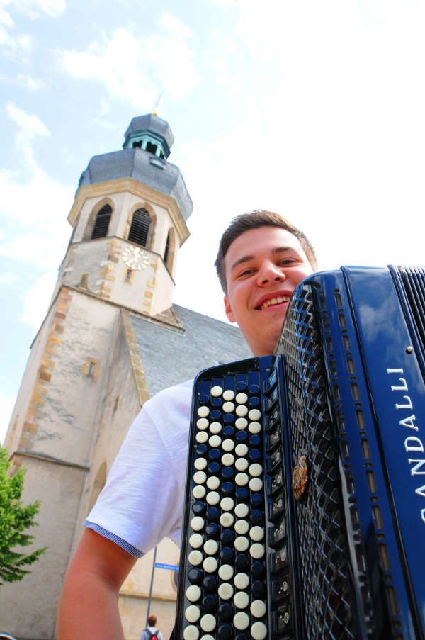 Junger Akkordeonist vor dem Turm der Stadtkirche in Bruchsal (Foto: DHV)