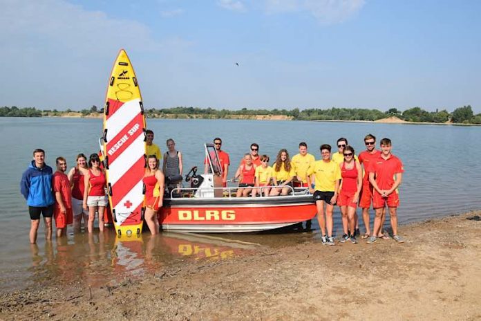 OB Schrempp (li.) und Nicole Würz (vordere Reihe, 3. v. re.) mit der Wachmannschaft des DLRG um das neue Boot am Epplesee. (Foto: Stadt Rheinstetten)