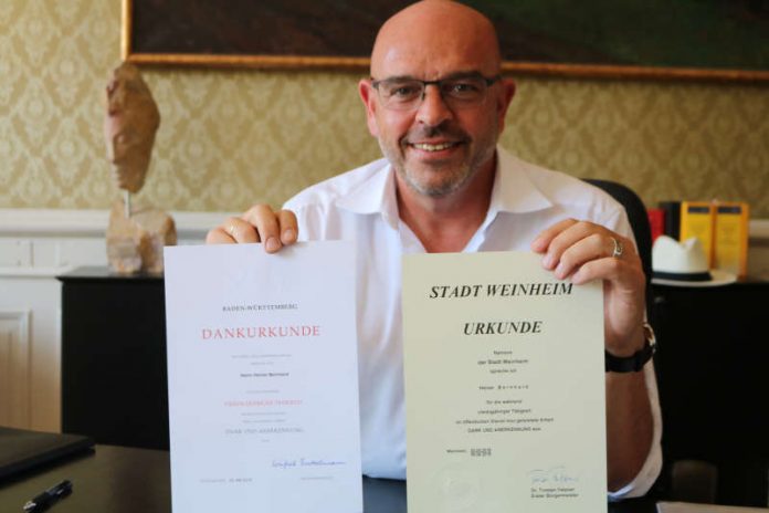 OB Heiner Bernhard mit zwei Urkunden (Foto: Stadtverwaltung Weinheim)