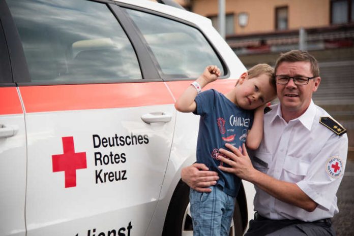 Rotkreuzsanitäter mit Kind und Bändchen Rotkreuzsanitäter mit Kind