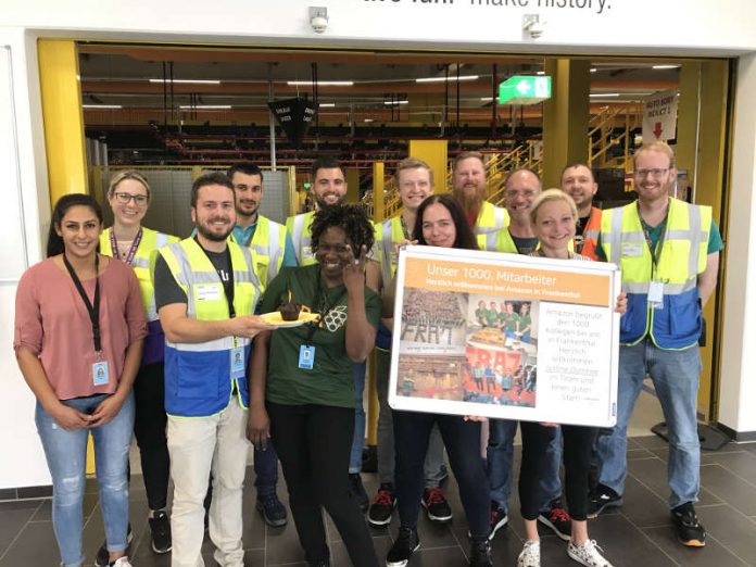 Standortleiter Johannes Weingärtner (Dritter von links) begrüßt mit seinem Team die 1000. Mitarbeiterin Justine Domkwe (im grünen T-Shirt) (Foto: AMAZON) Standortleiter Johannes Weingärtner (Dritter von links) begrüßt mit seinem Team die 1000. Mitarbeiterin Justine Domkwe (im grünen T-Shirt) (Foto: AMAZON)