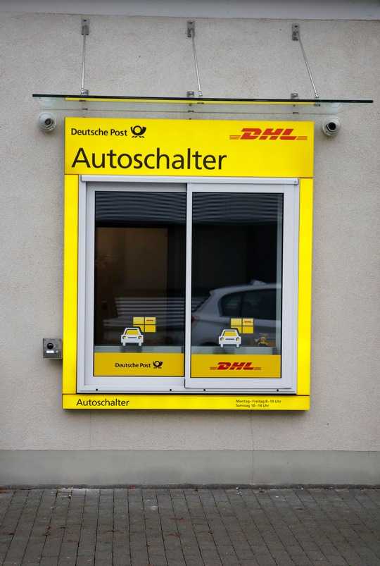 Bequemer geht es nicht: Pakete empfangen und versenden ohne aus dem Auto aussteigen zu müssen. Die Deutsche Post testet den bundesweit ersten Autoschalter in Bad Kreuznach. Als einer der ersten Kunden nahm Gregor Lind sein Paket direkt im Auto in Empfang. Rechts im Bild: Andreas Paulus, Filialpartner der Deutschen Post in Bad Kreuznach. (Fotohinweis: Deutsche Post DHL)