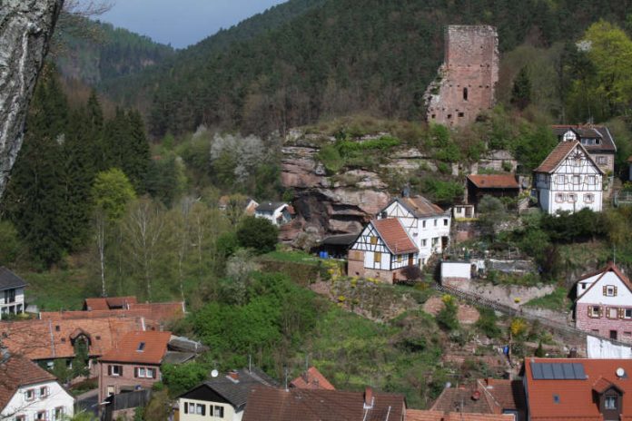 Blick vom Rehfelsen zur Burgruine Elmstein, links unten sieht man die Dächer der Mühle und Wappenschmiede, ein früheres Mühlenensemble mit ehemals fünf Wasserrädern an einem vom Speyerbach abgezweigten Kanal. (Bild: Benno Münch)