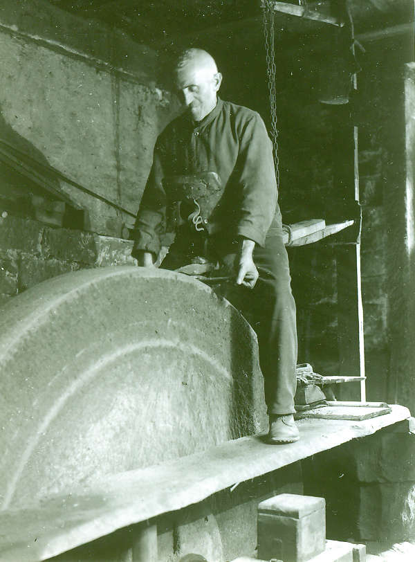 Hammerschmied Daniel Haag beim Schärfen eines Werkzeugs am großen Schleifstein um 1928 (Bild: Archiv Wappenschmiede)