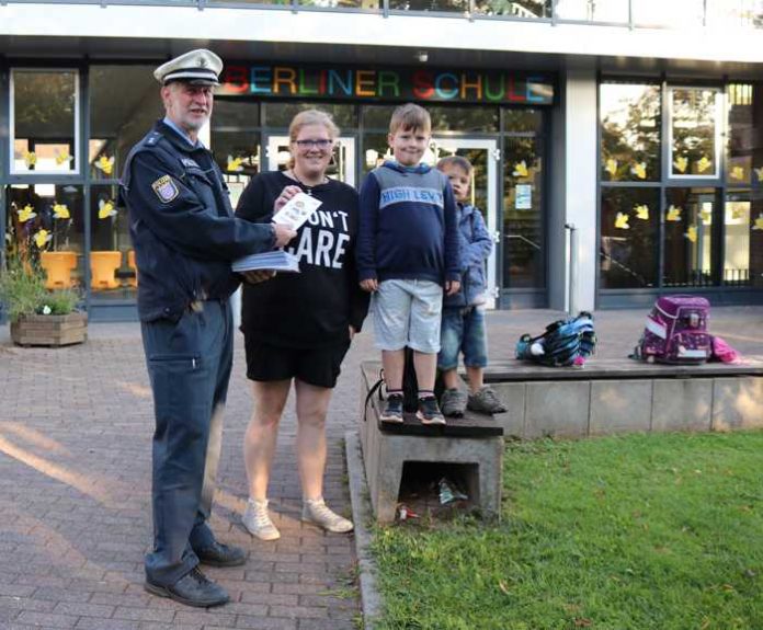 Uwe Maier von der Jugendverkehrsschule übergibt einer Mutter, die ihre beiden Kinder zur Schule bringt, einen Flyer vom Kinderkommissar LEON Uwe Maier von der Jugendverkehrsschule übergibt einer Mutter, die ihre beiden Kinder zur Schule bringt, einen Flyer vom Kinderkommissar LEON
