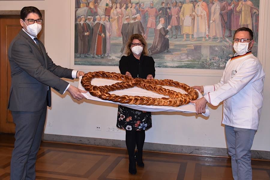 Bäckermeister Becker (r.) überreichte Landaus OB Hirsch auch in diesem Jahr eine riesige Neujahrsbrezel als Glücksbringer. Gleichstellungsbeauftragte Evi Julier brachte die Brezel anschließend ins Frauenhaus. (Quelle: Stadt Landau)