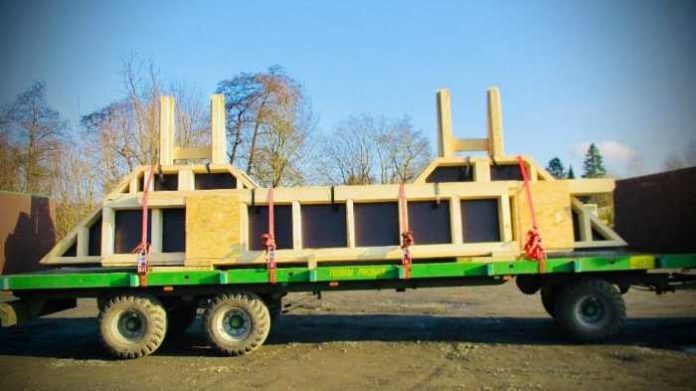 Landwirtschaftlicher Anhänger hat Teile eines ganzen Holzhauses geladen