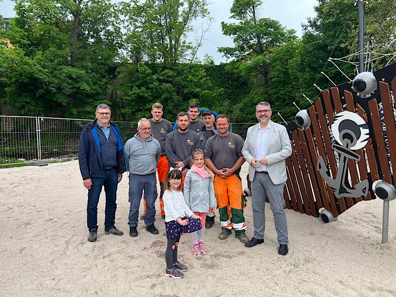 OB Marc Weigel (re.) mit Mitarbeitern der Abteilung Grünflächen, die den neuen Spielplatz gebaut haben. Ganz rechts Grünflächenchef Michael Fuhrer. Anastasia und Charlotte waren die ersten Besucherinnen und vom neuen Spielplatz begeistert. (Foto: Stadtverwaltung Neustadt)