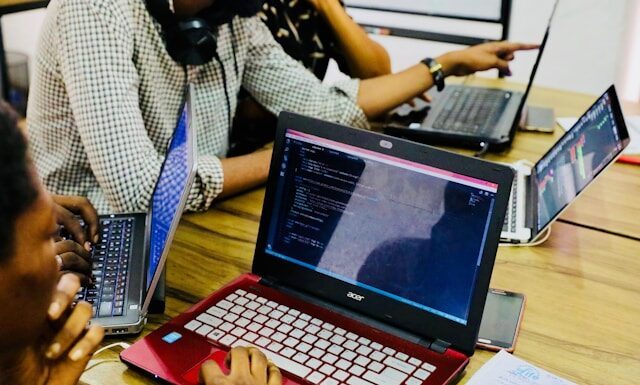 Betriebssysteme im Vergleich: Welche Lösung passt zu welchem Nutzer? Person mit schwarzem und rotem Acer-Laptop auf dem Tisch (Unsplash / Desola Lanre-Ologun)