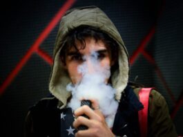 Junger Mann, der eine Vape dampft